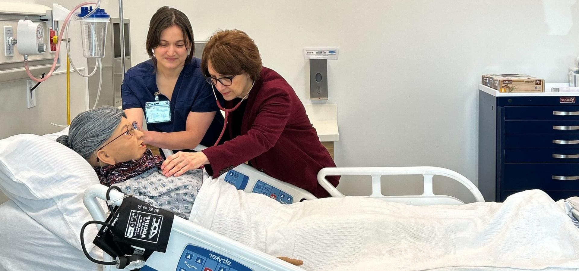 A TBCC staff member guides Rep Bonamici through checking the lungs of a dummy patient used in their healthcare classes. 